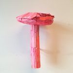 A whimsical sculpture of a pink mushroom crafted from textured wood fragments.
